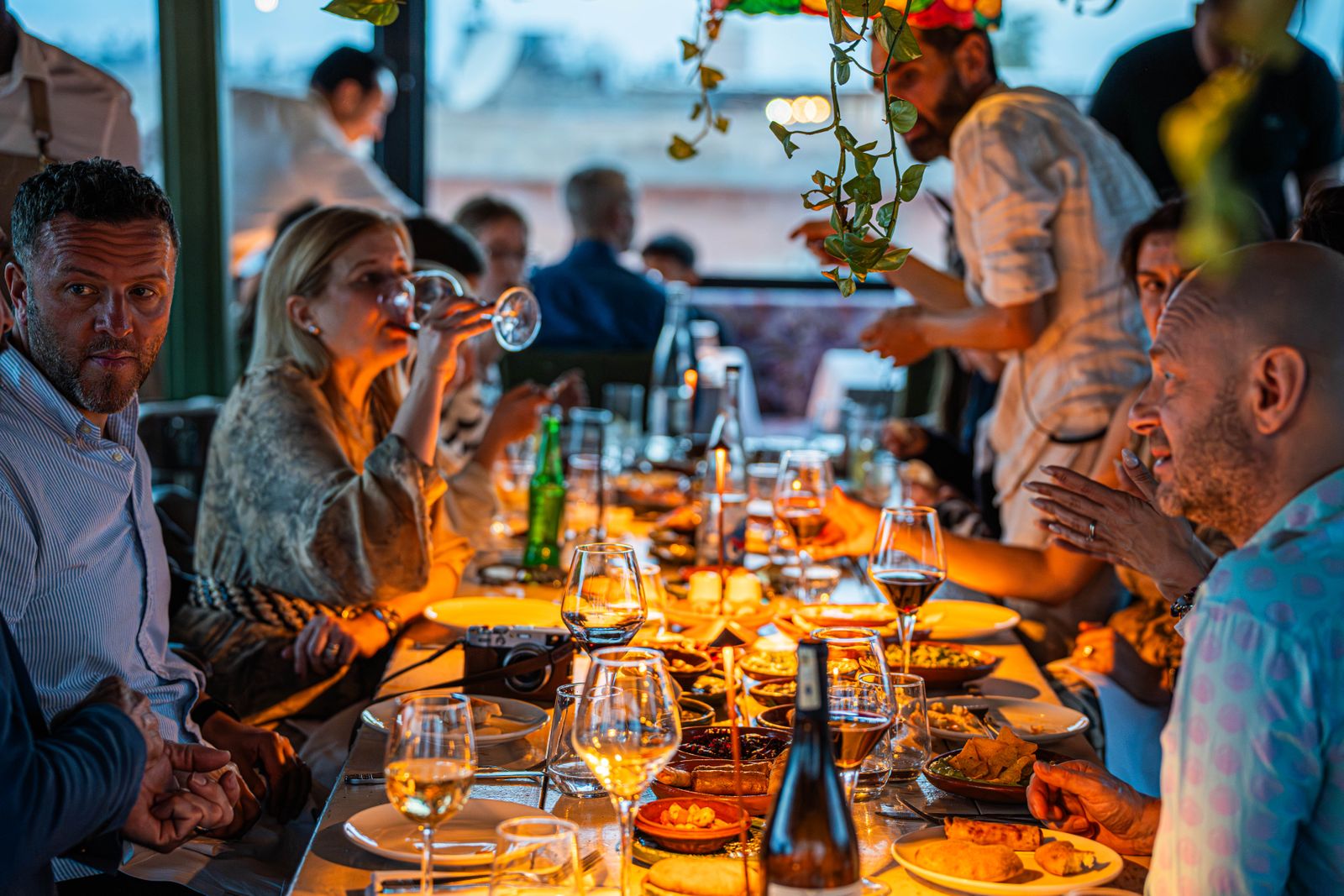 A lively gathering of friends enjoying a candlelit dinner with wine and conversation.