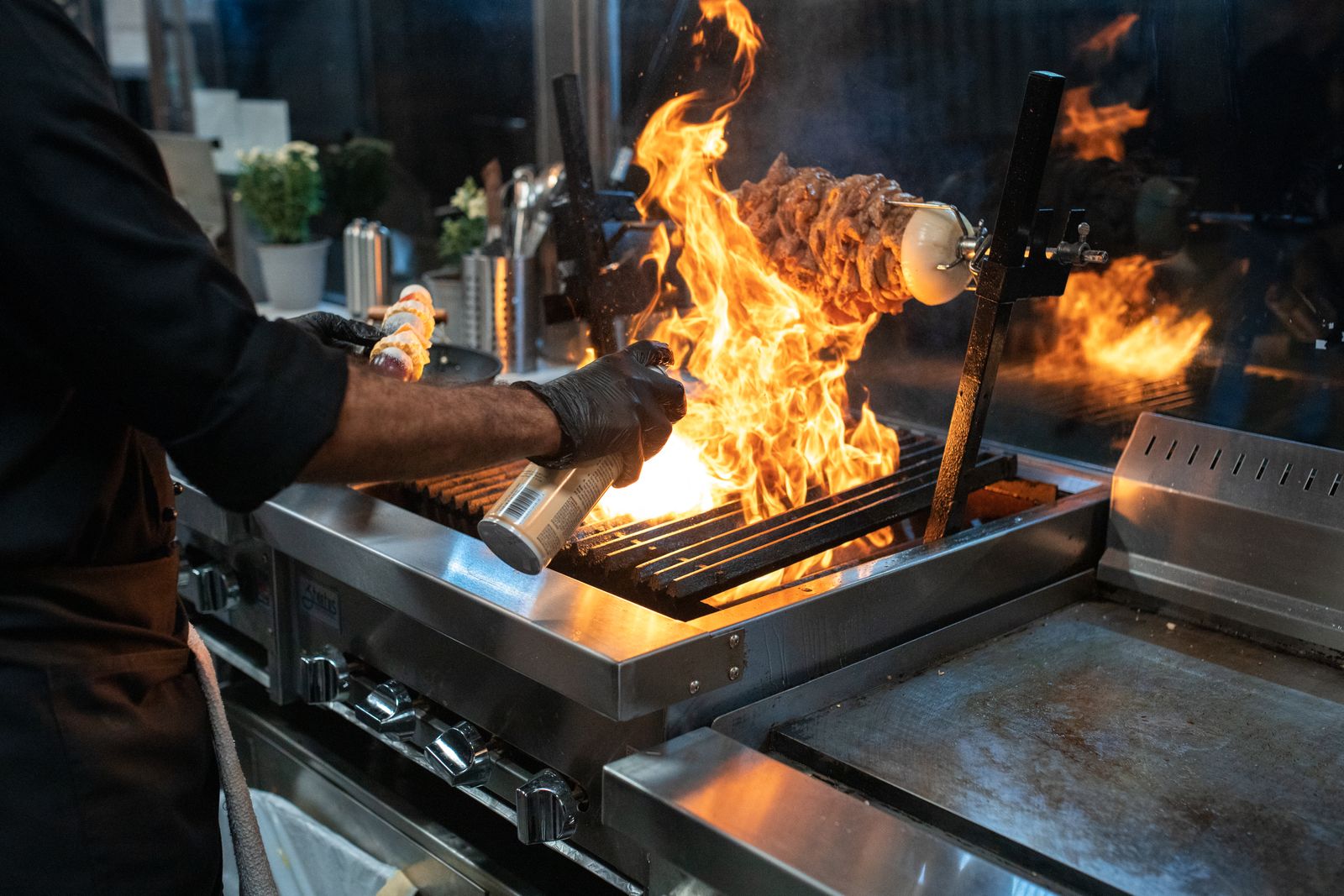 Chef grilling meat with spectacular flames in a modern kitchen setup.